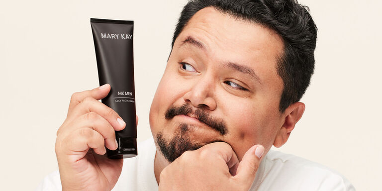 Male model holding the MKMens Daily Facial Wash tube up to his face