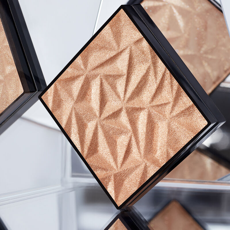 Limited-edition Mary Kay Illuminating Highlighter in shade Golden Glow surrounded by mirrors and product reflections image number null