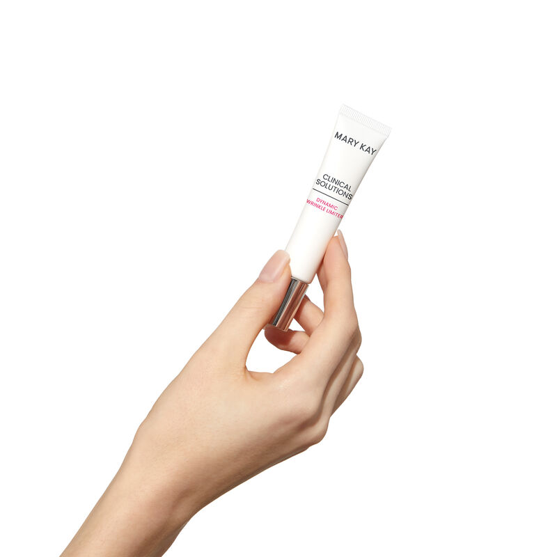 Fair-skinned hand holding tube of Mary Kay Clinical Solutions Dynamic Wrinkle Limiter against a plain background