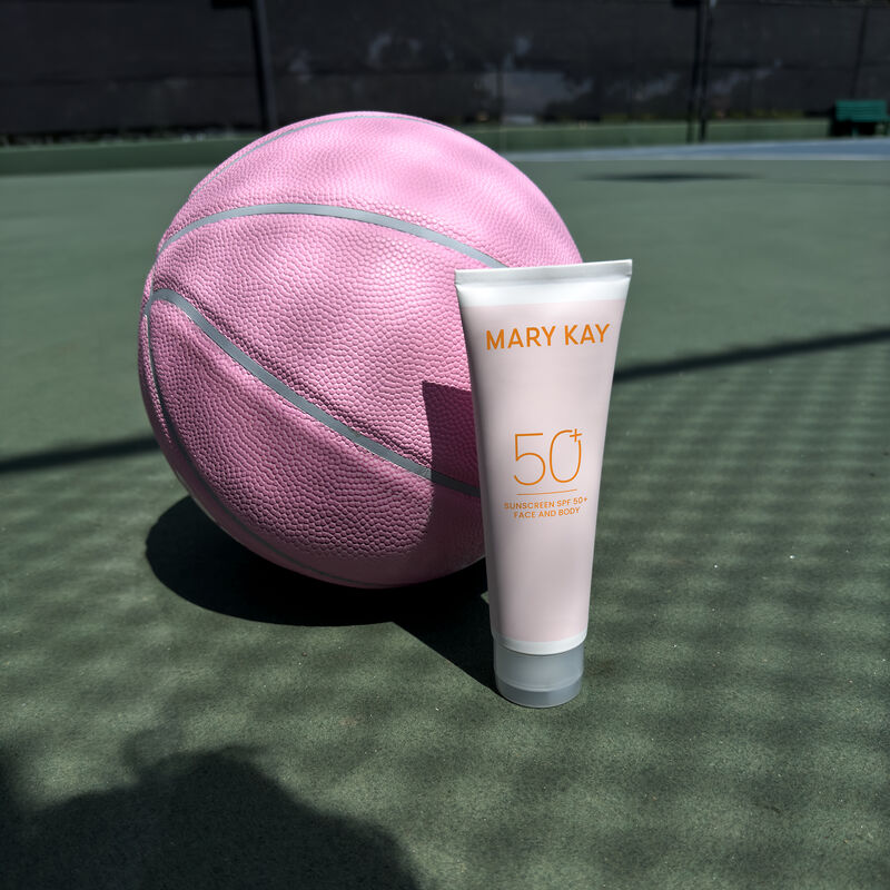 Bottle of Mary Kay&reg; Sunscreen SPF 50+ in front of pink basketball on a sports court