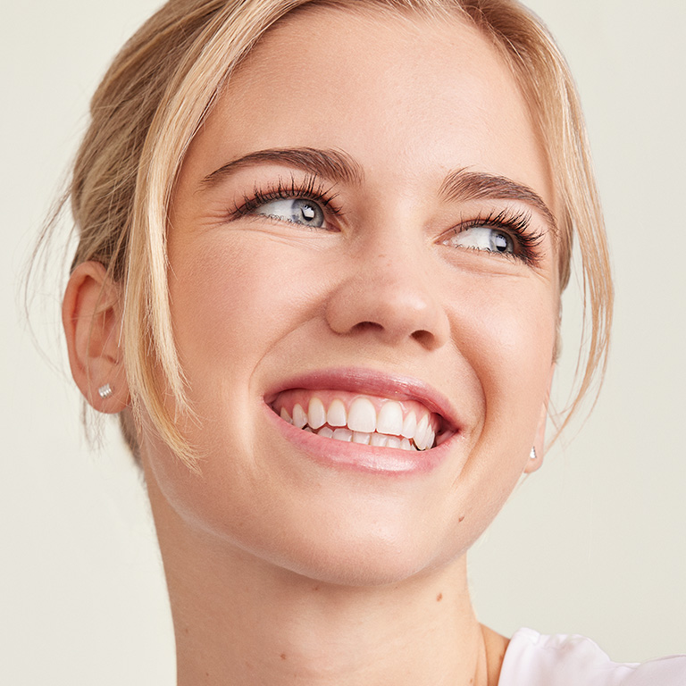 Fair skinned model smiling to the side of the camera