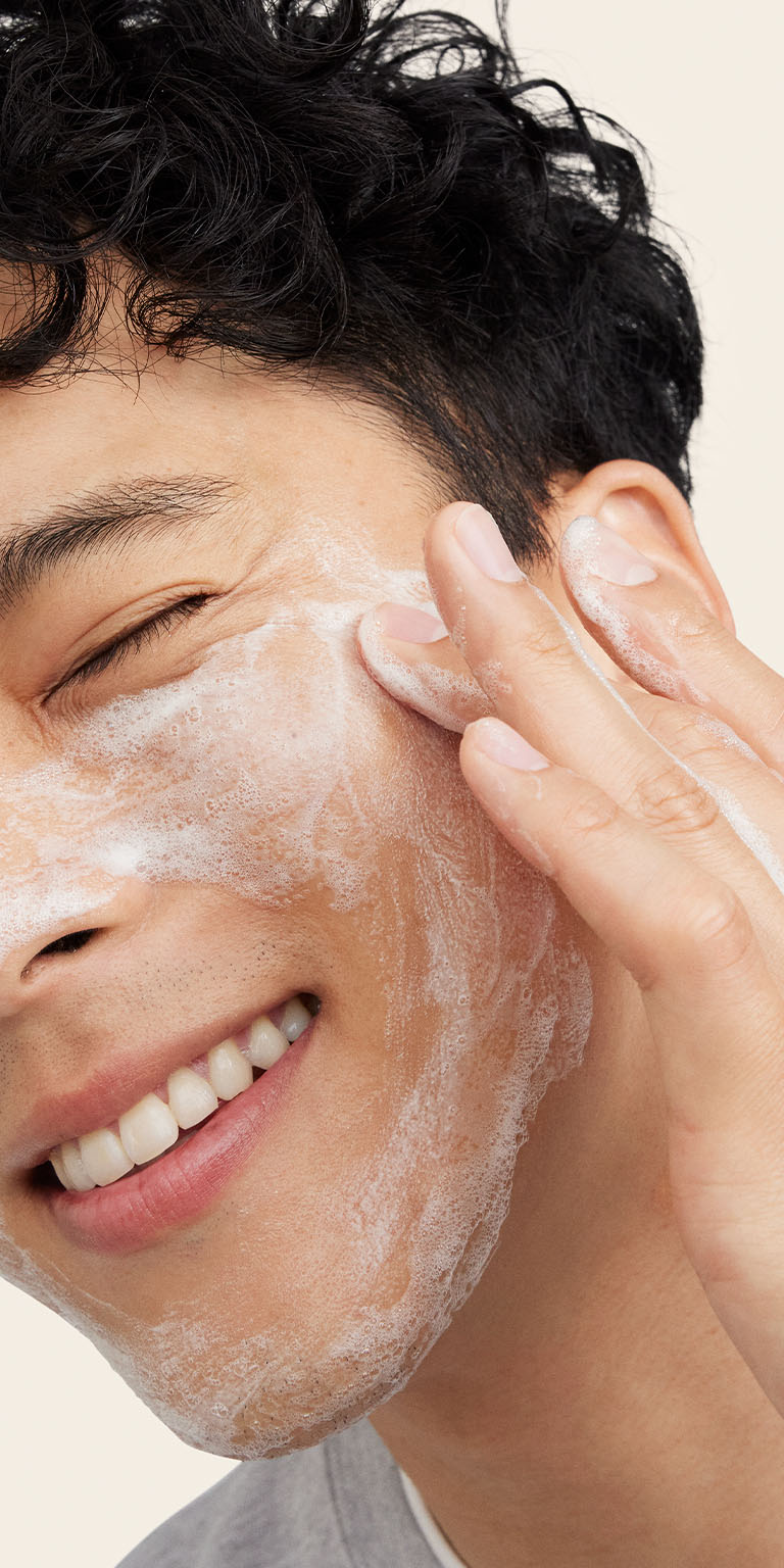 Male model applying MKMens facial wash to the side of his face