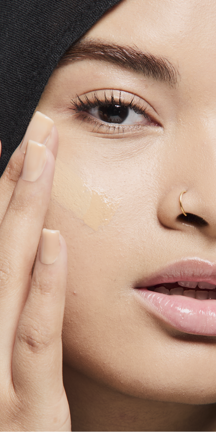 Medium skin tone model applying foundation.